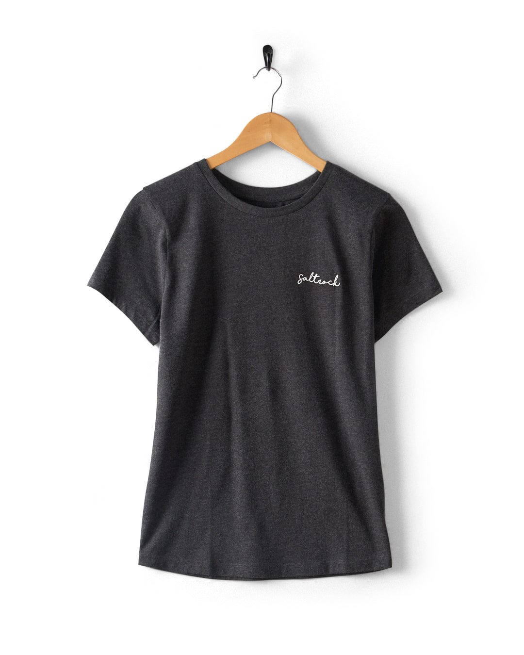 The Velator Women's Short Sleeve T-Shirt by Saltrock is a dark grey tee made from recycled materials, with a peached soft feel and small white Saltrock script on the left chest, shown on a wooden hanger against a white background.