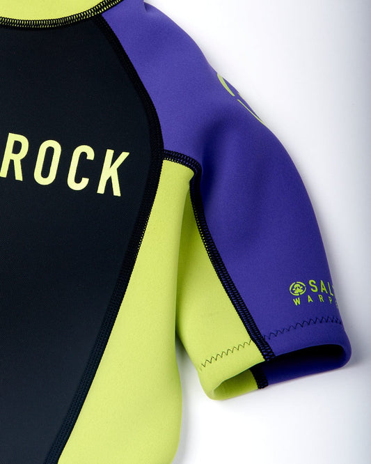 Close-up of a black, purple, and neon yellow neoprene wetsuit with the brand "Saltrock Warped" visible on the sleeve.