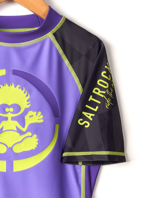 Close-up of a purple Saltrock Warp Icon print rash guard with black and neon green accents, featuring a detailed graphic design and logo.