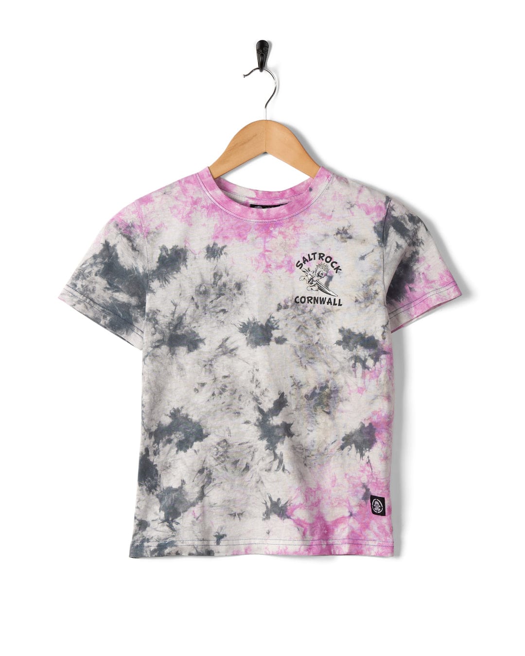 A Wave Rider Cornwall - Kids Tie Dye Short Sleeve T-Shirt in pink featuring Saltrock branding with black and pink patterns on a hanger against a white background.