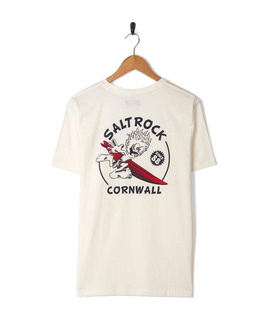 A Wave Rider Cornwall white t-shirt hanging on a wall hook, featuring Saltrock branding with the text "Saltrock Cornwall" and an illustration of a surfer.