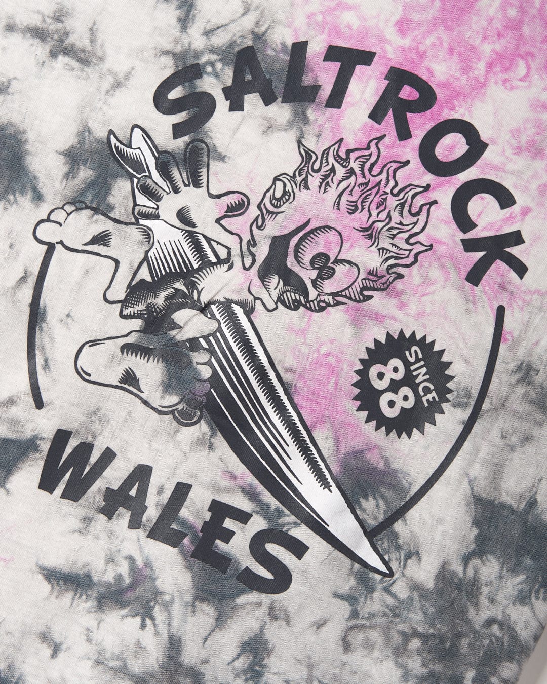 Graphic print on a Wave Rider Wales 100% Cotton tie-dye shirt featuring Saltrock branding and the text "wales" with an illustration of a dragon and a surfboard.