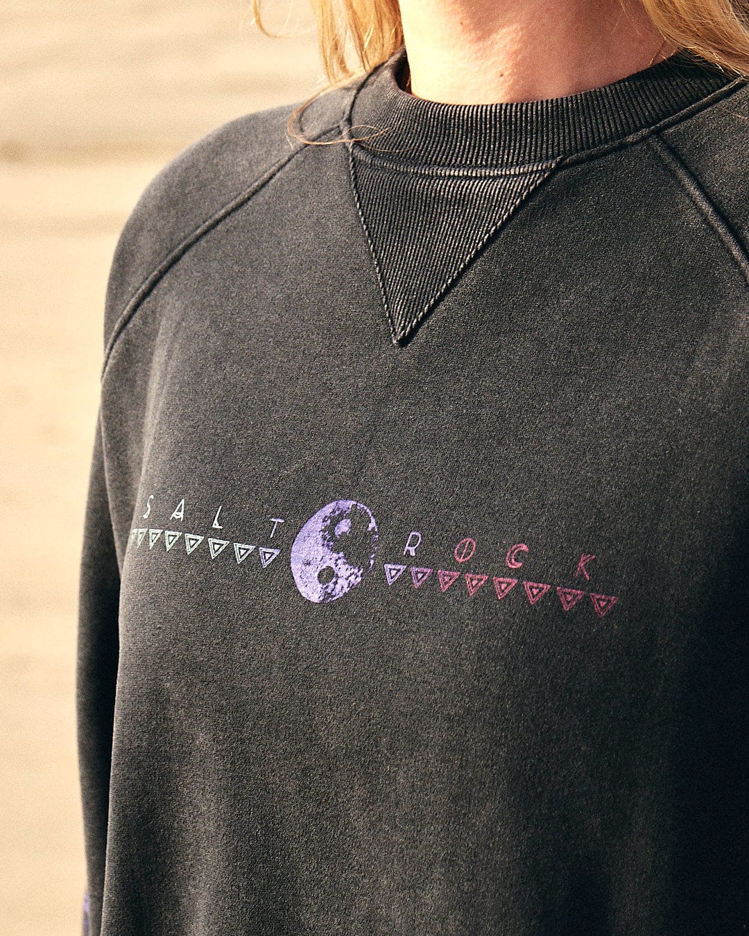 A woman wearing a Saltrock Winter Solstice Gradient - Womens Sweat - Washed Black with a purple heart on it during winter.