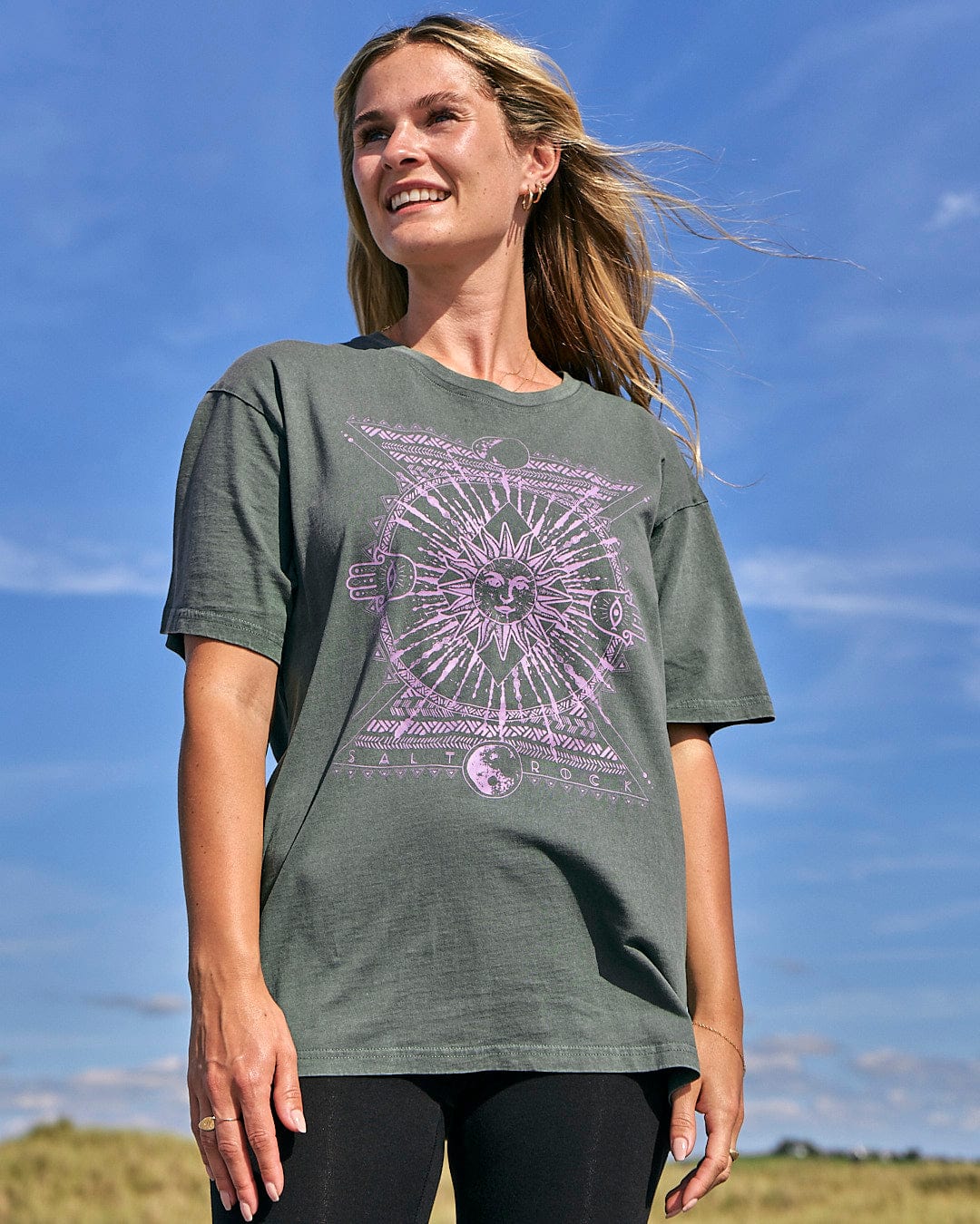 A woman wearing a purple Saltrock Winter Solstice Tee standing in a field.