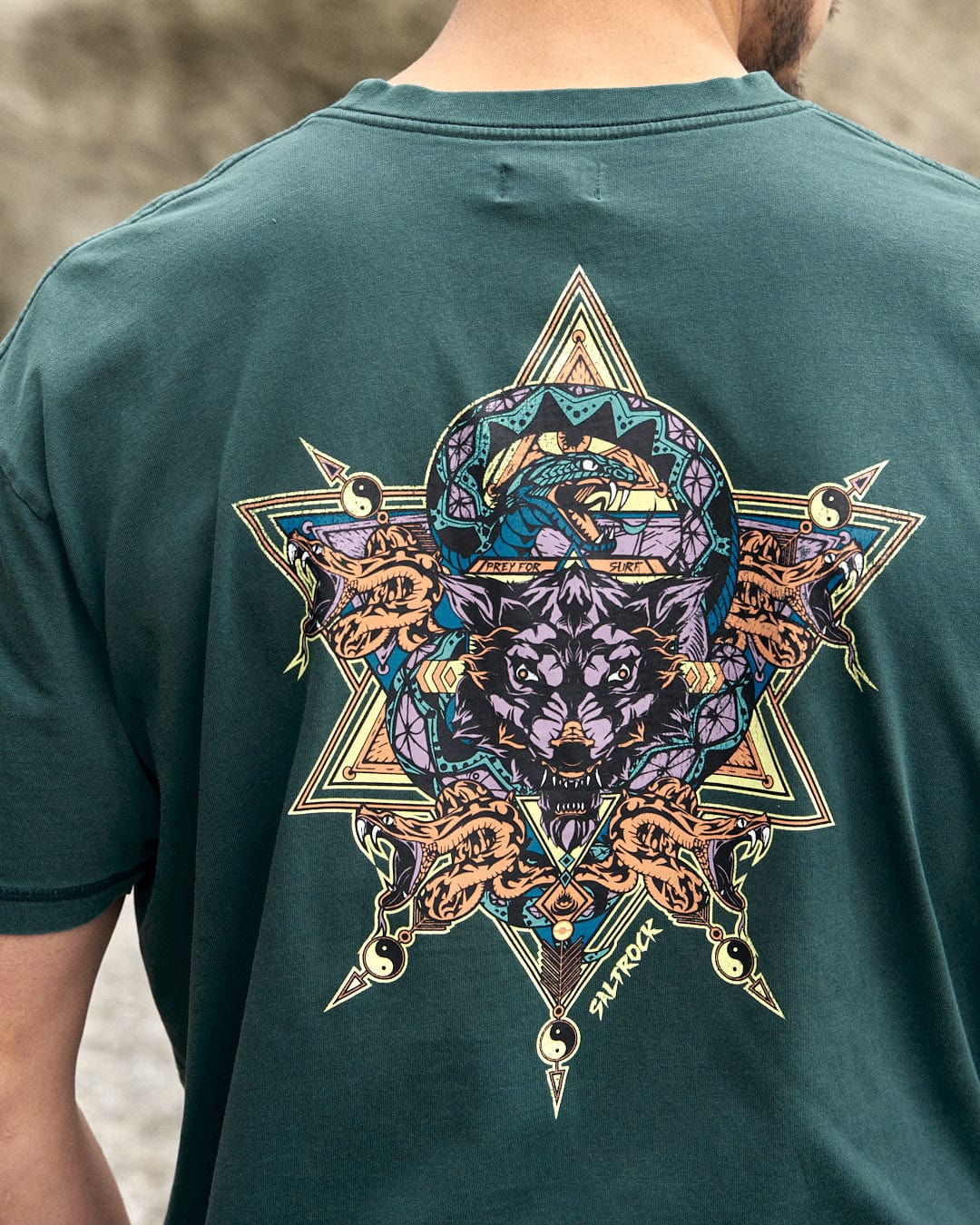 The back of a man wearing a Saltrock Wolfscale Mens Short Sleeve T-Shirt in Dark Green with a wolf print.
