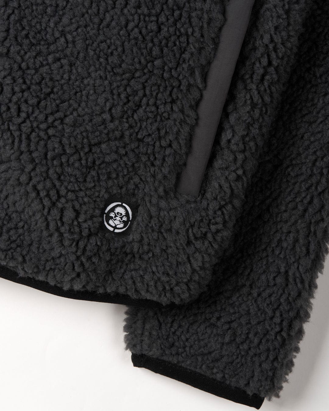 Close-up of a textured Wyer - Kids Fleece - Zip - Dark Grey with a Saltrock badge.