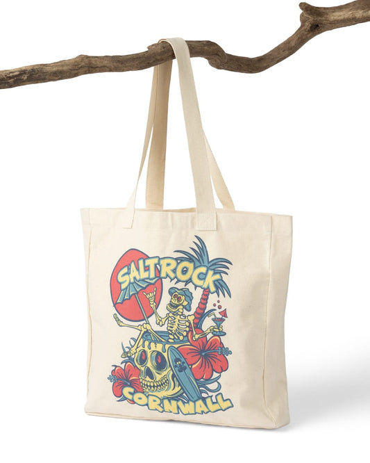 Tote bag with a colorful design featuring a skeleton, umbrella, and text 'Salt Rock Cornwall' hanging on a branch.