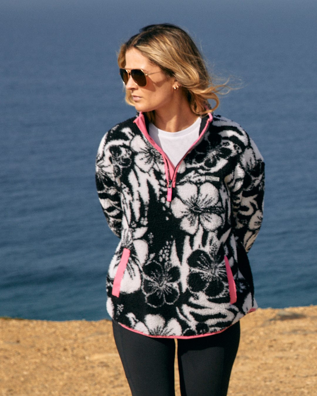 A woman wearing a Zella Hibiscus - Womens 1/4 Neck Fleece - Black Floral made by Saltrock.