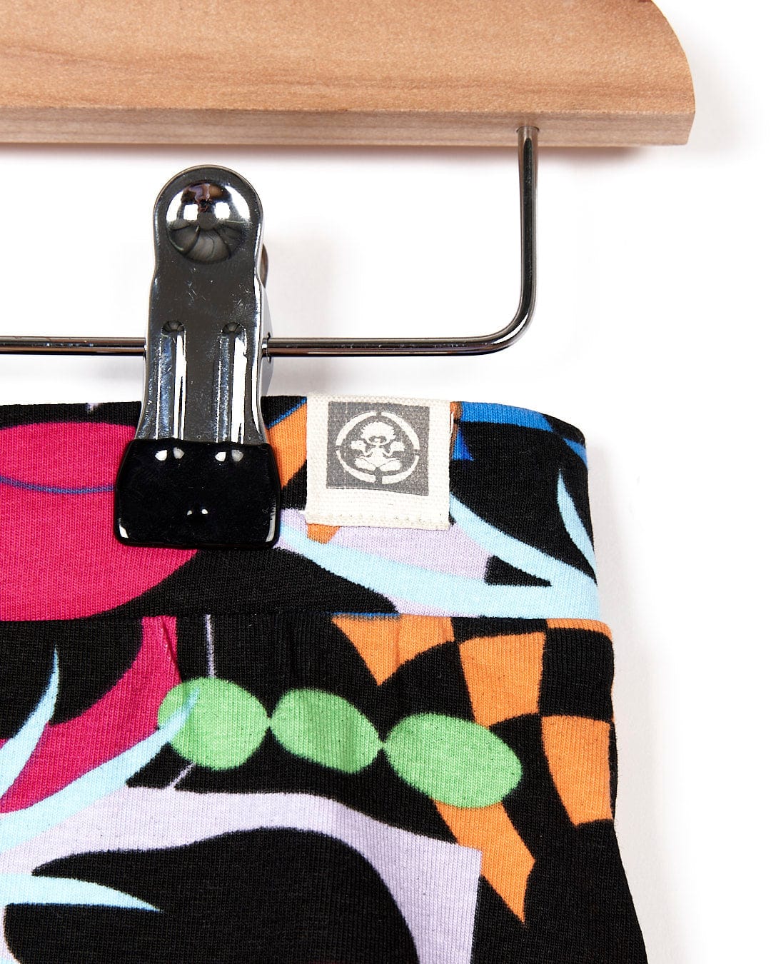 A pair of Zephyr - Kids Leggings - Black by Saltrock hanging on a wooden hanger.