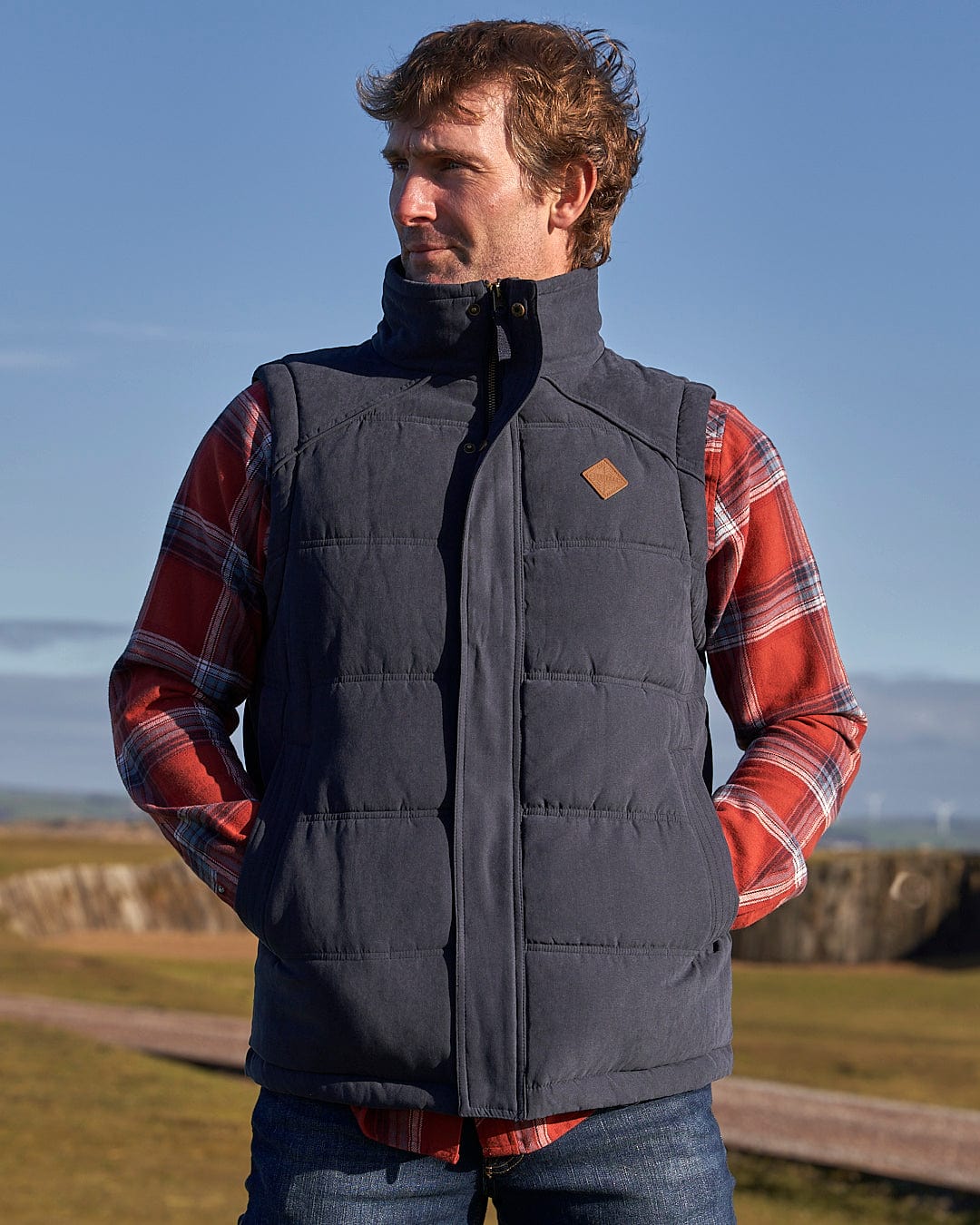 A man is standing in a field wearing a Saltrock Bardsey - Mens Gilet - Blue.
