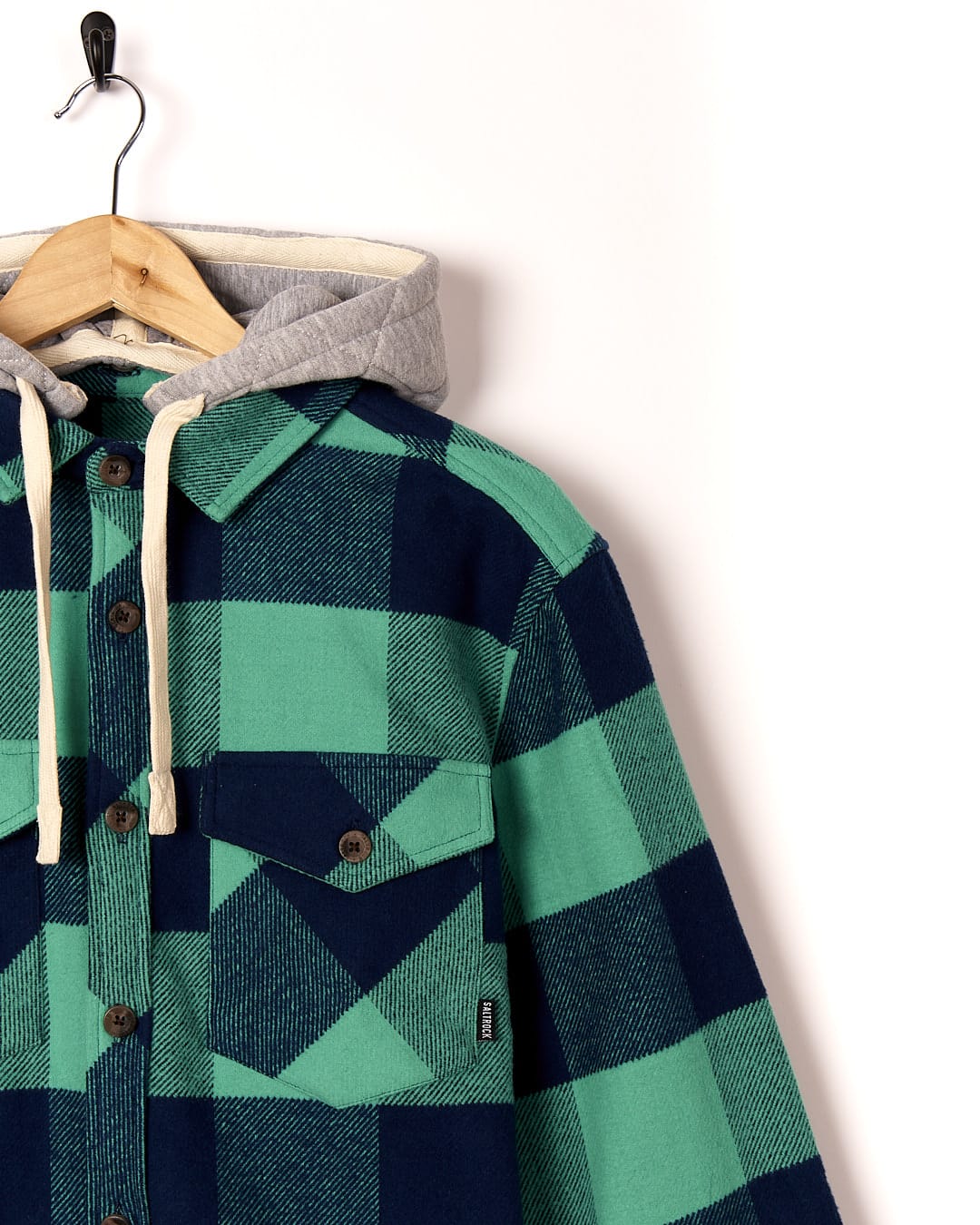 A Saltrock - Beale Mens Heavy Weight Hooded Shirt - Dark Green hanging on a hanger.