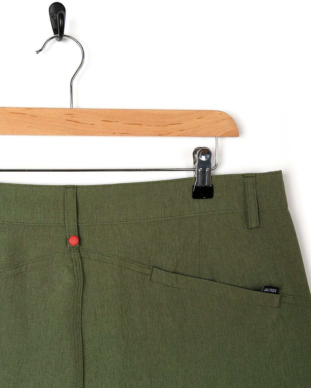 A pair of Saltrock Cargo Amphibian II - Mens Boardshort - Dark Green shorts hanging on a hanger.