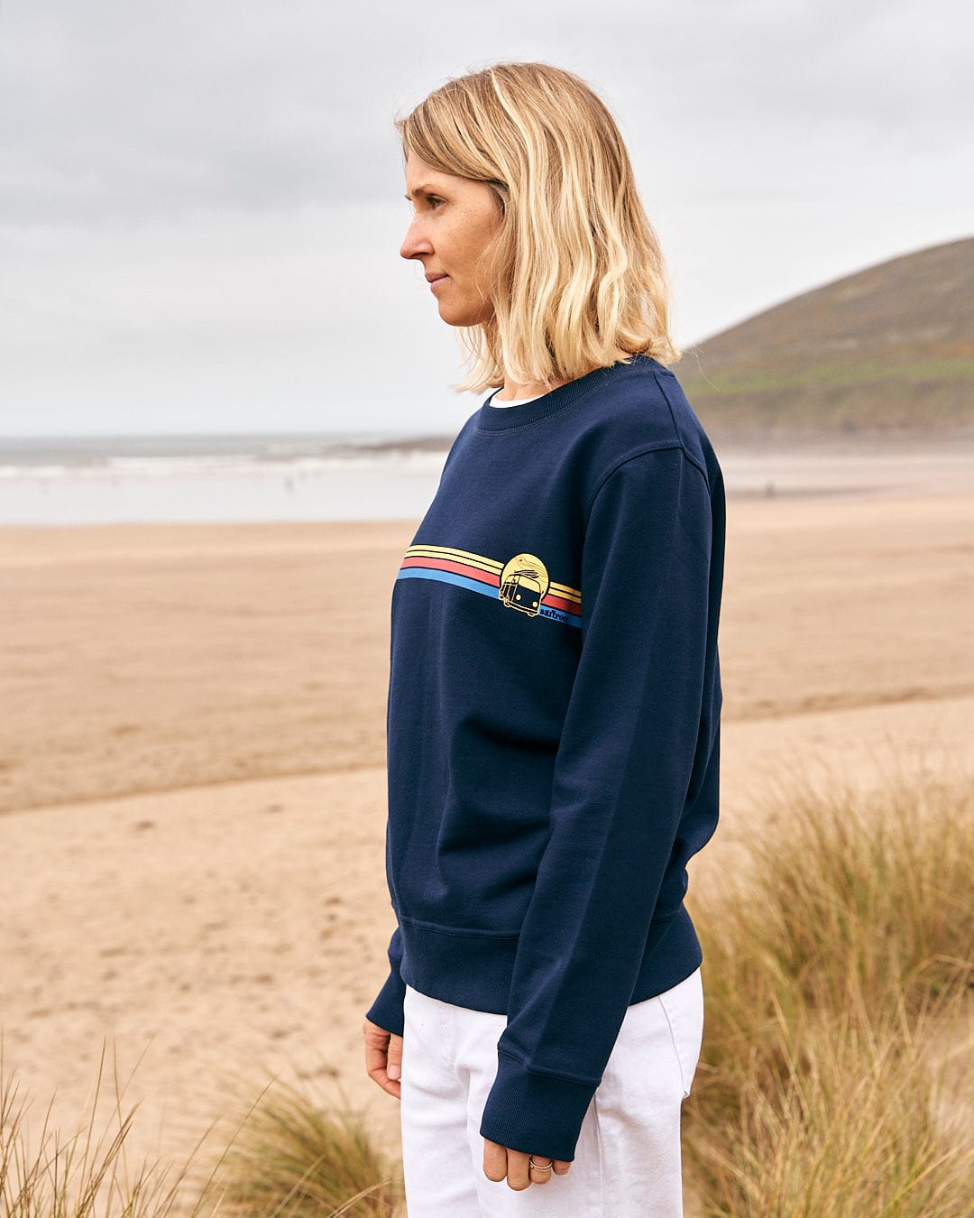 A woman wearing a Saltrock Celeste Stripe - Womens Crew Sweat - Blue standing on the beach.