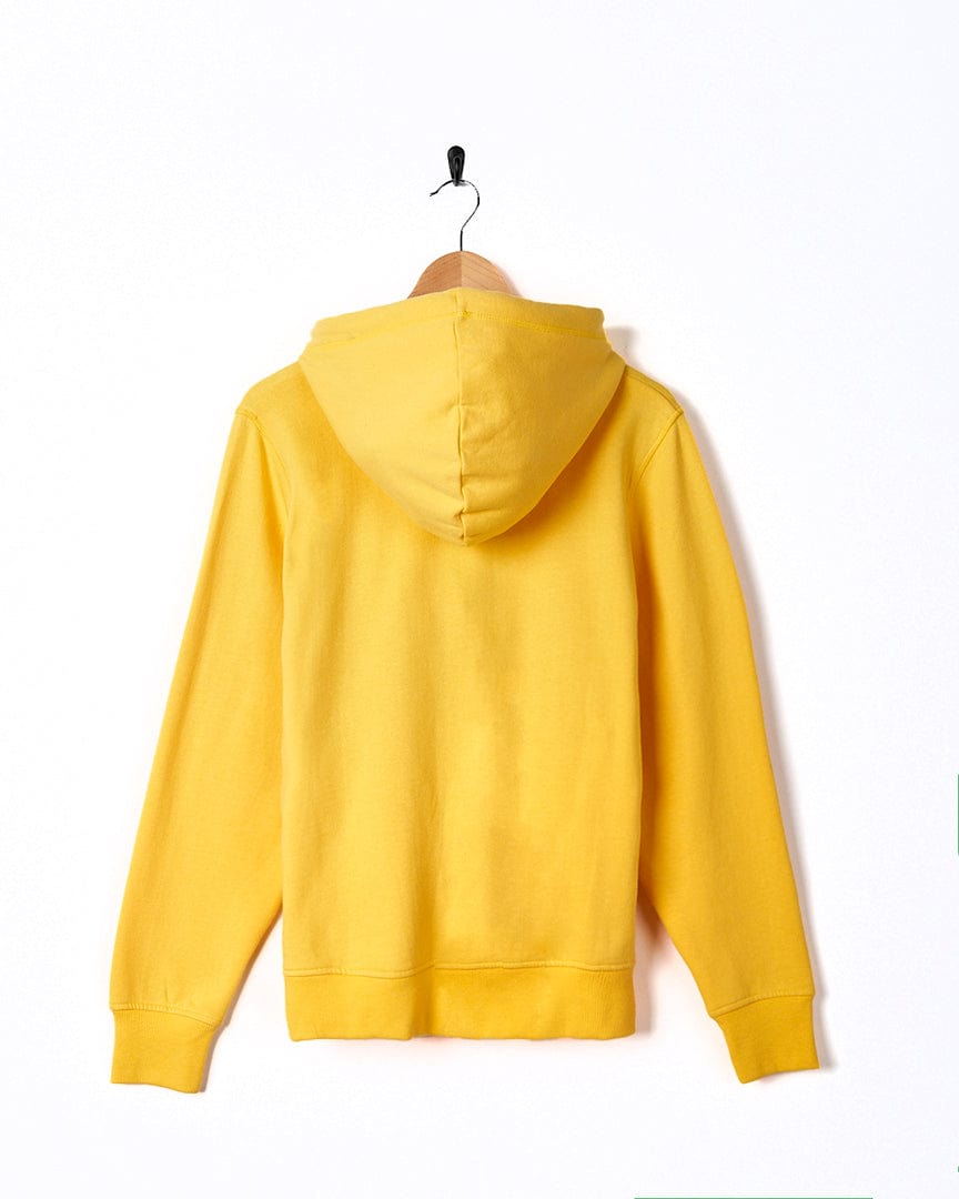 A Dreamseeker - Womens Pop Hoodie in yellow, by Saltrock, hanging on a white wall.