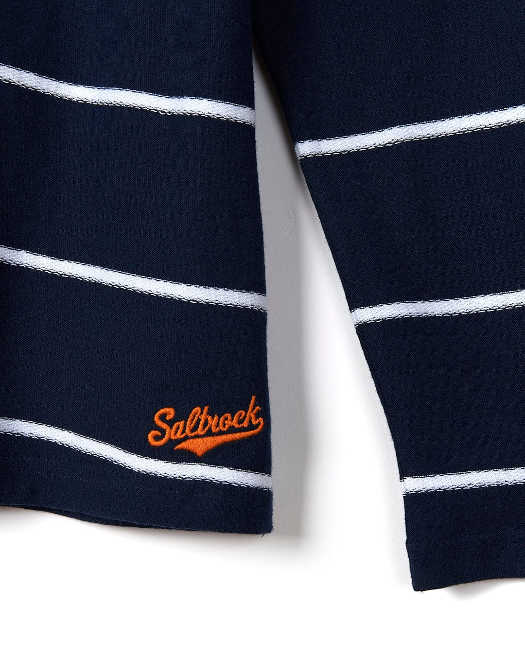 Close-up of a navy blue Saltrock cardigan with white horizontal stripes and an embroidered logo on the left cuff, creating a nautical look.