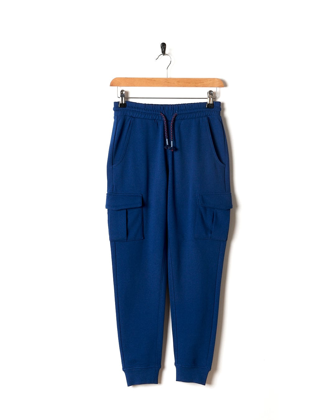 A Jakub - Kids Cargo Trouser - Blue by Saltrock hanging on a hanger.