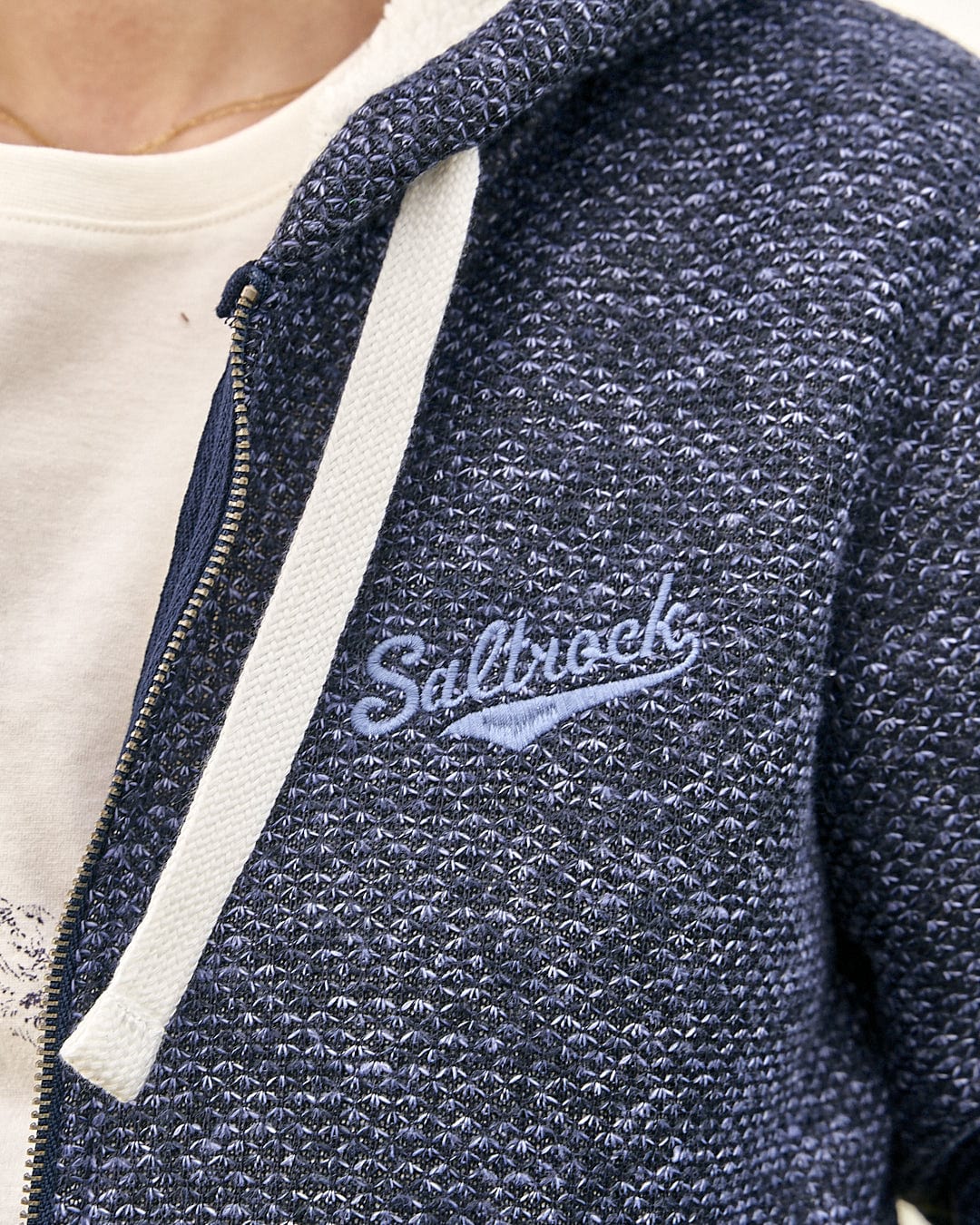 A woman wearing a Saltrock Jazz - Womens Borg Lined Zip Hoodie - Dark Blue with a logo on it.