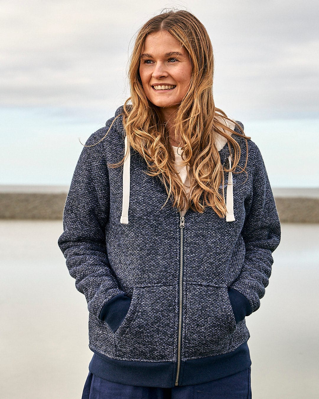 A woman wearing a Saltrock Jazz - Womens Borg Lined Zip Hoodie - Dark Blue and jeans.