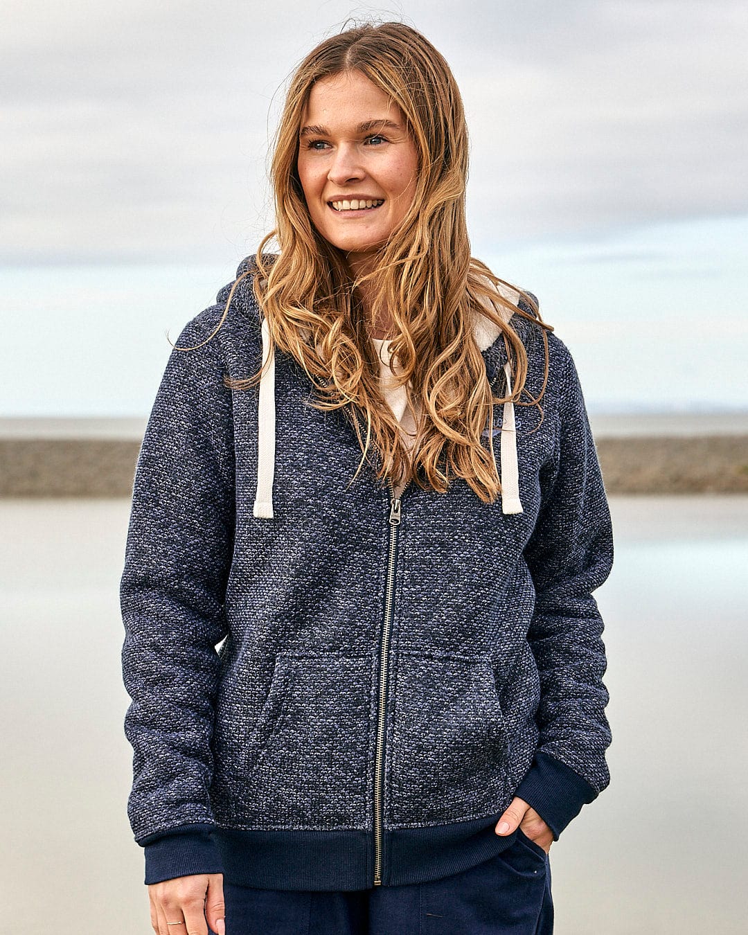 A woman wearing a Saltrock Jazz Womens Borg Lined Zip Hoodie in Dark Blue and sweatpants.
