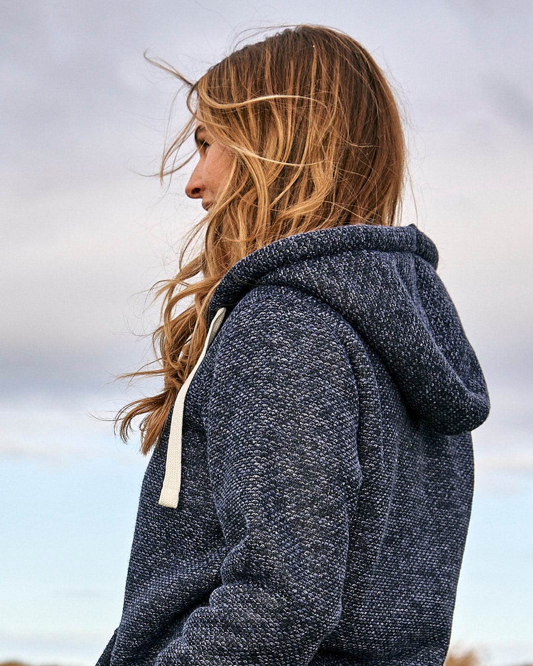 A woman in a Saltrock Jazz - Womens Borg Lined Zip Hoodie - Dark Blue standing on a beach.