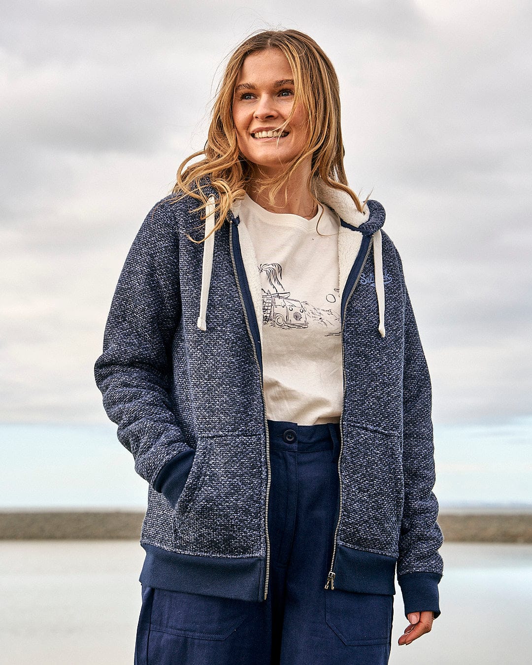 A woman wearing a Saltrock Jazz - Womens Borg Lined Zip Hoodie - Dark Blue and jeans.