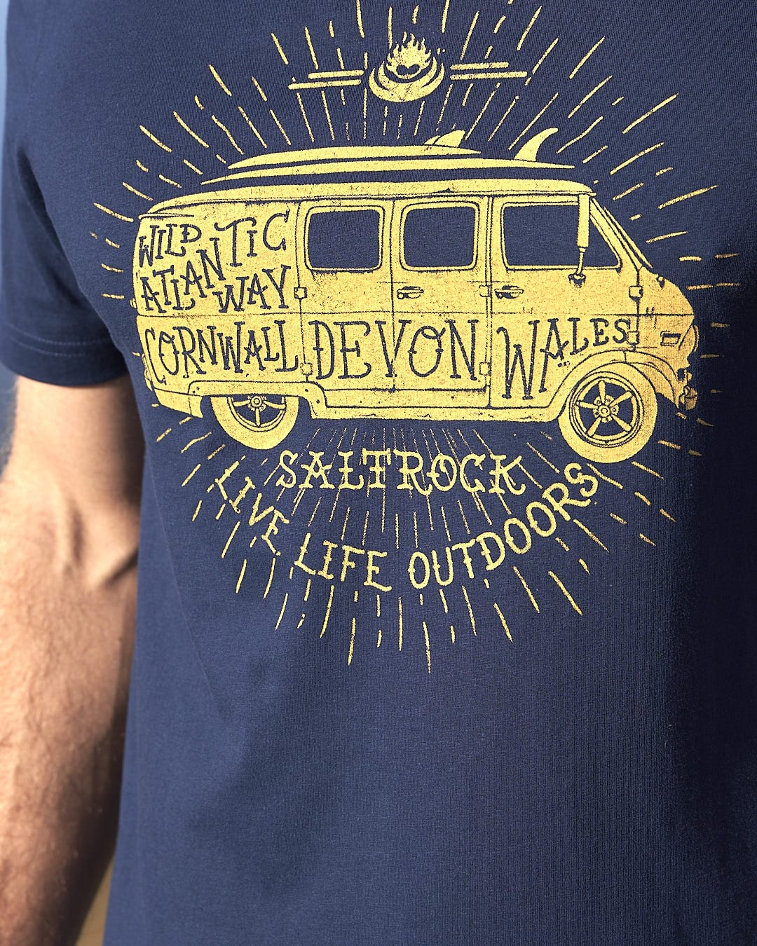 A man wearing a Saltrock Live Life Location - Mens Short Sleeve T-Shirt - Blue with a van on it.
