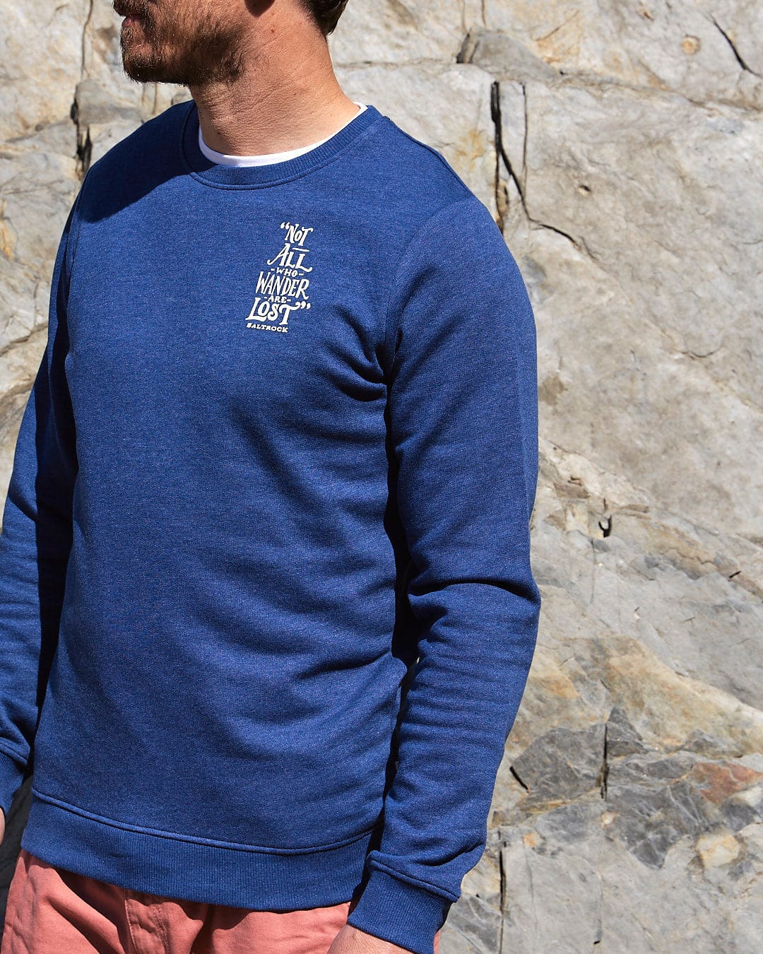 A man wearing a Saltrock Lost Ships - Mens Crew Sweat - Dark Blue sweatshirt and pink shorts.