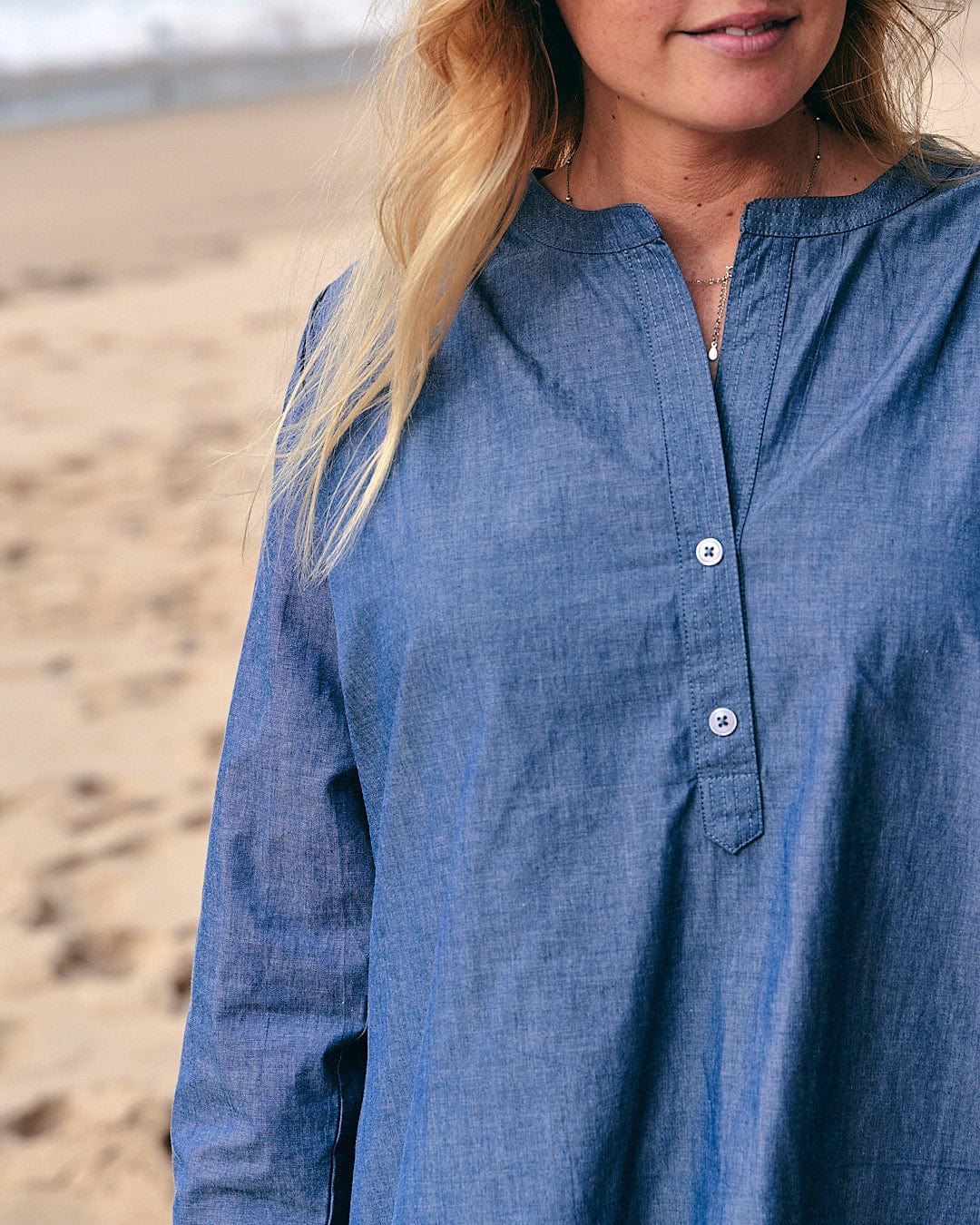 A woman is standing on the beach wearing a Manina - Womens Beach Shirt - Blue by Saltrock.
