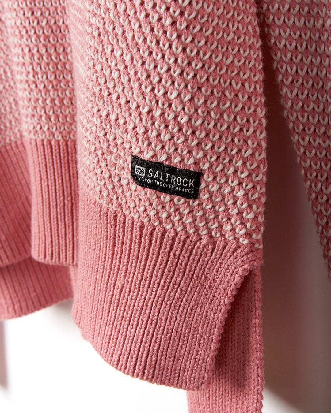 A Poppy - Womens Knitted Pop Hoodie - Mid Pink sweater hanging on a wall, by Saltrock.