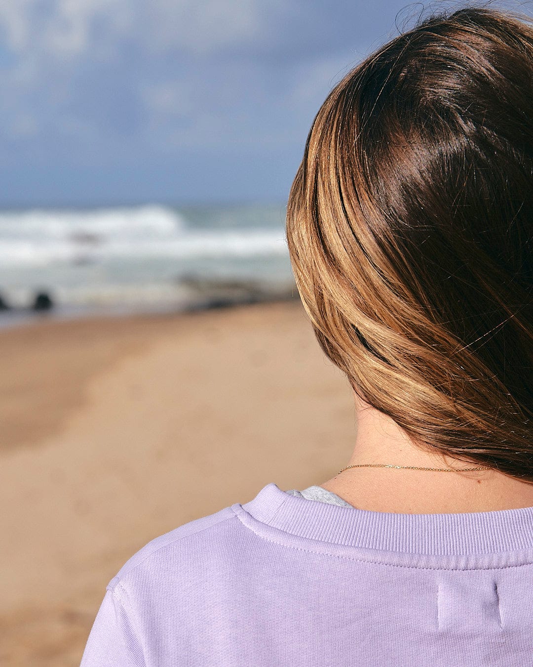 A woman is standing on a beach with a Saltrock Poster Stripe - Womens Crew Sweat - Light Purple.