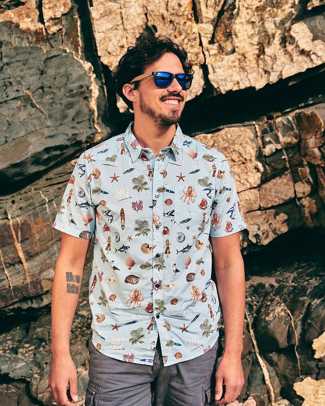 A man wearing sunglasses and a Ruan - Mens Washed Short Sleeve Shirt from Saltrock with birds on it.