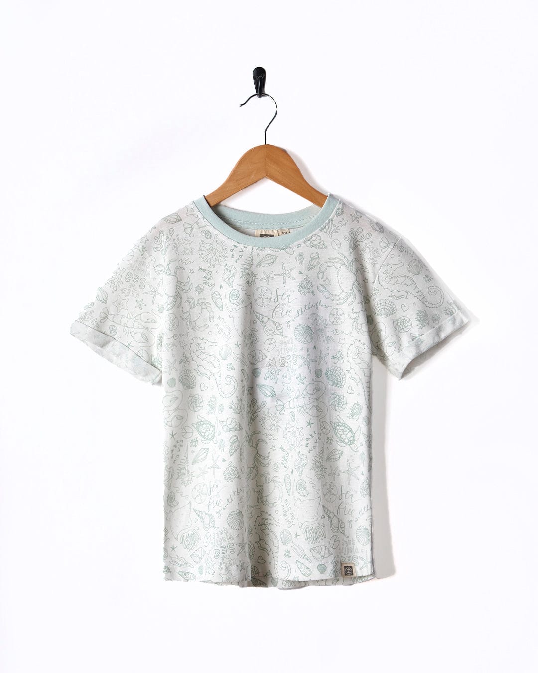 A Seashore - Kids All Over Print Short Sleeve T-Shirt - White hanging on a wooden hanger. Brand Name: Saltrock.