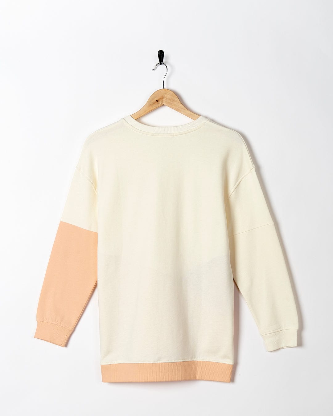 A Saltrock Sofie - Womens Boyfriend Fit Sweat - Light Orange/Cream sweatshirt hanging on a hanger.