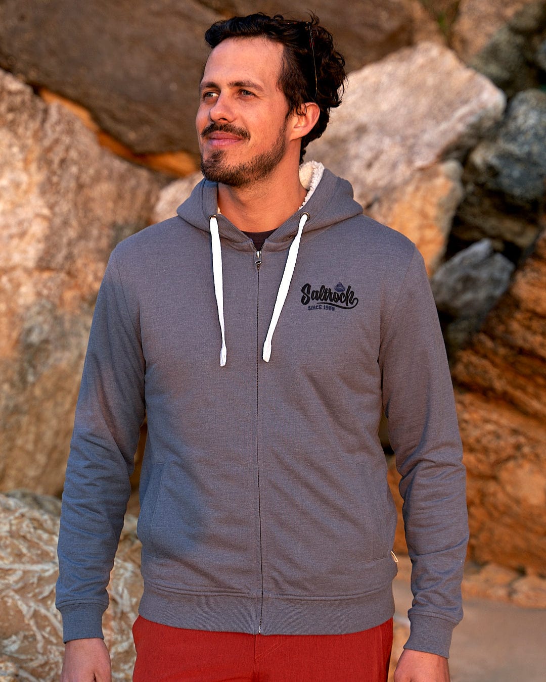 A man wearing a Speed - Mens Borg Lined Hoodie - Grey zip up hoodie and red shorts.
Brand Name: Saltrock