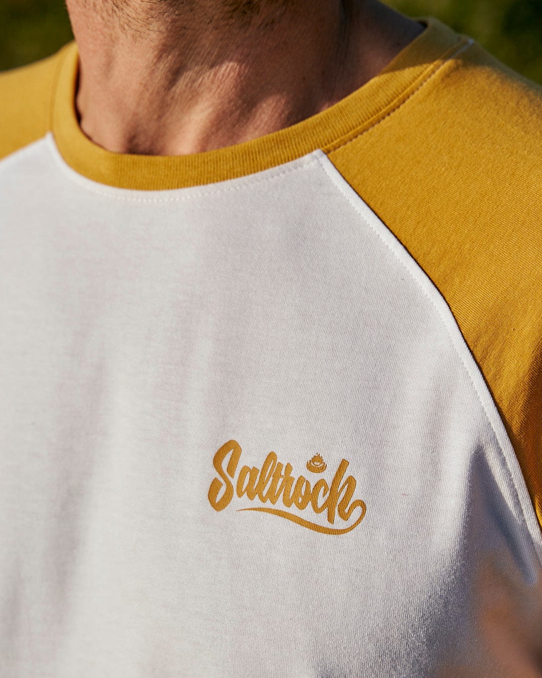 A man wearing a Saltrock Speed - Mens Long Sleeve Raglan T-Shirt in Ochre/White.