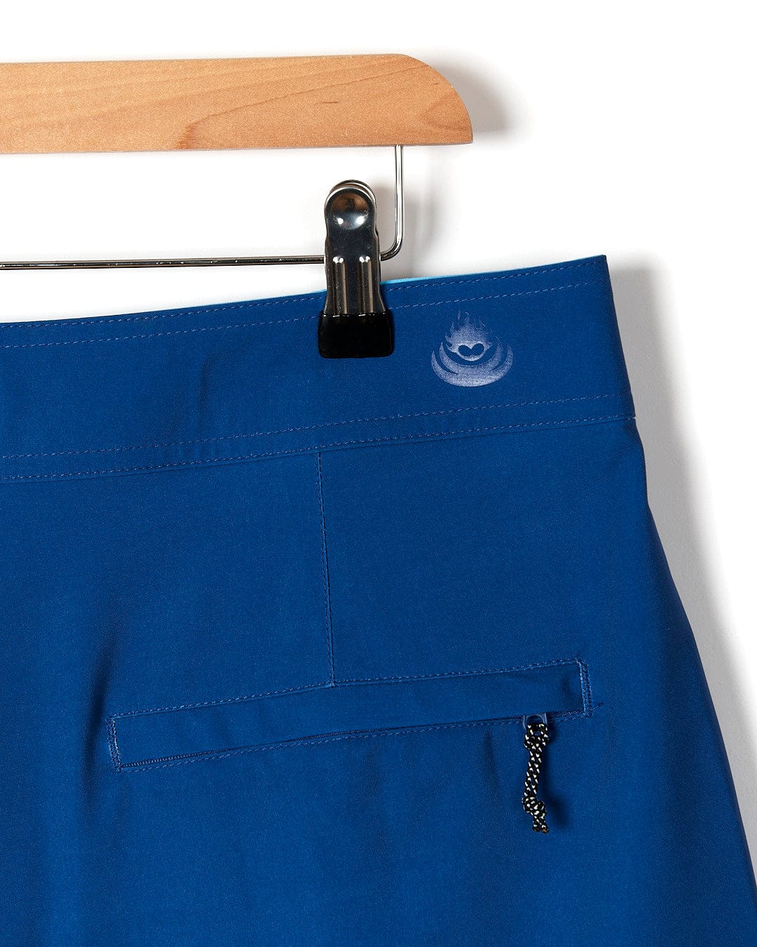 A Splash Gradient - Mens Boardshort - Dark Blue by Saltrock hanging on a hanger.