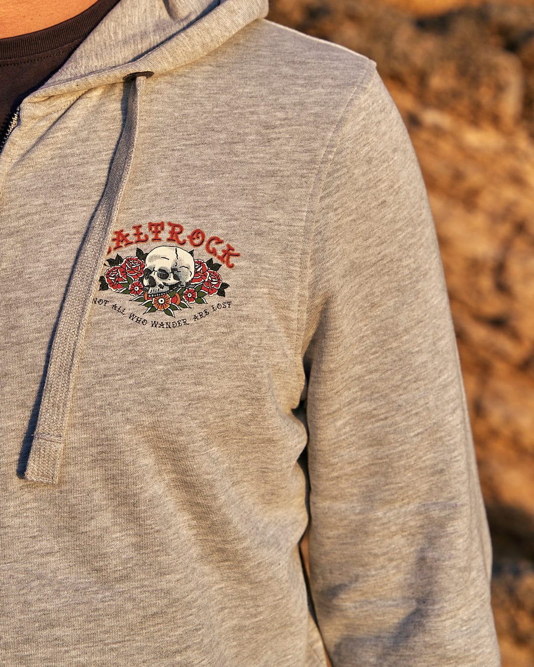 A man wearing a Saltrock Tattoo Island - Mens Zip Hoodie in Grey with a skull on it.