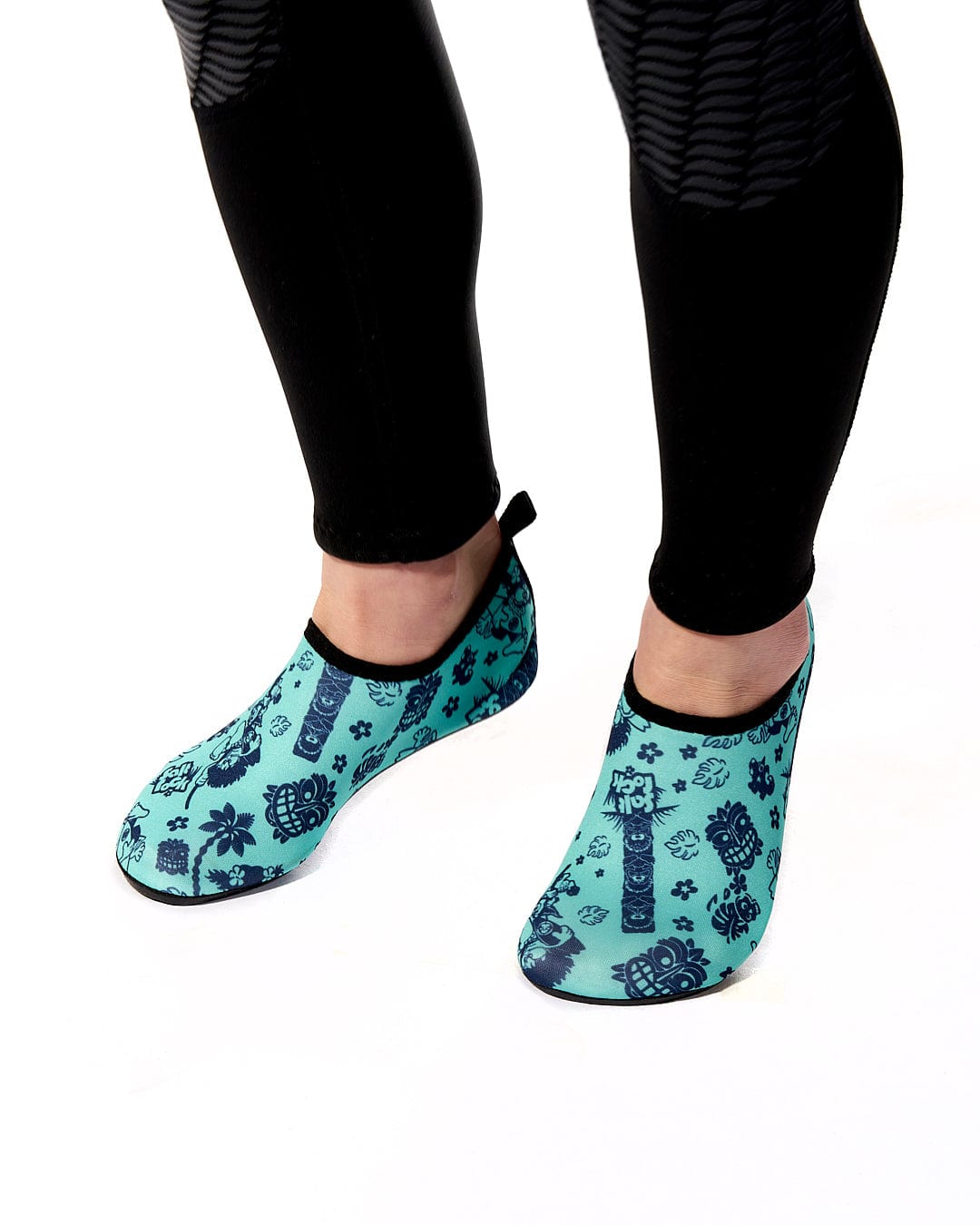 A woman wearing black leggings and a pair of Saltrock Tiki Tok - Kids Aqua Shoe - Turquoise socks.