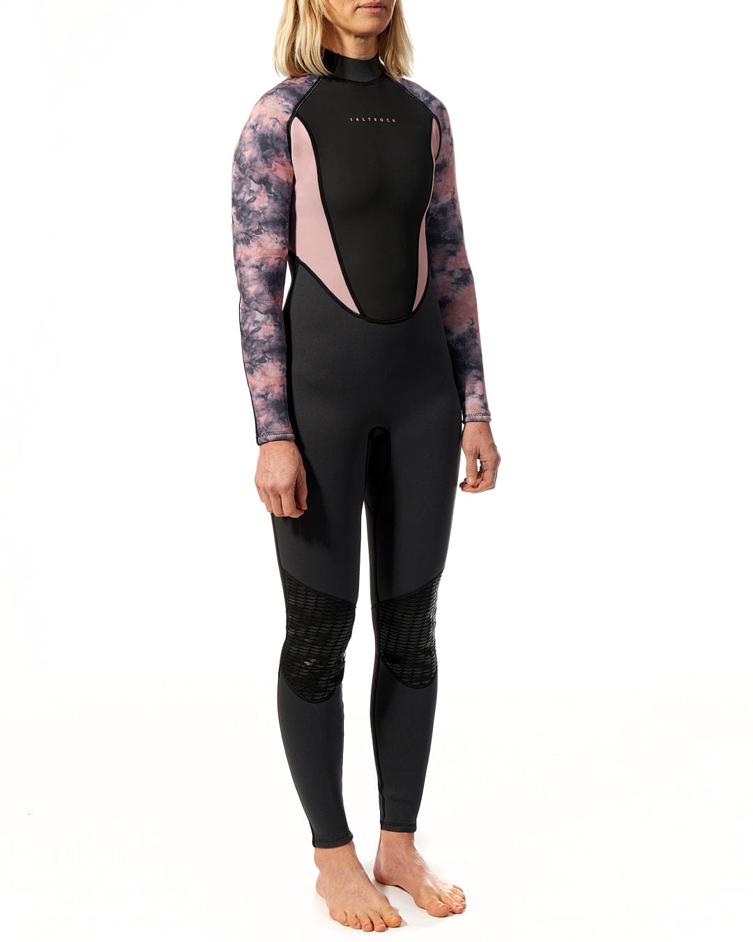 A woman wearing the Saltrock Vision - Womens 3/2 Back Zip Wetsuit - Black/Pink standing on a white background.