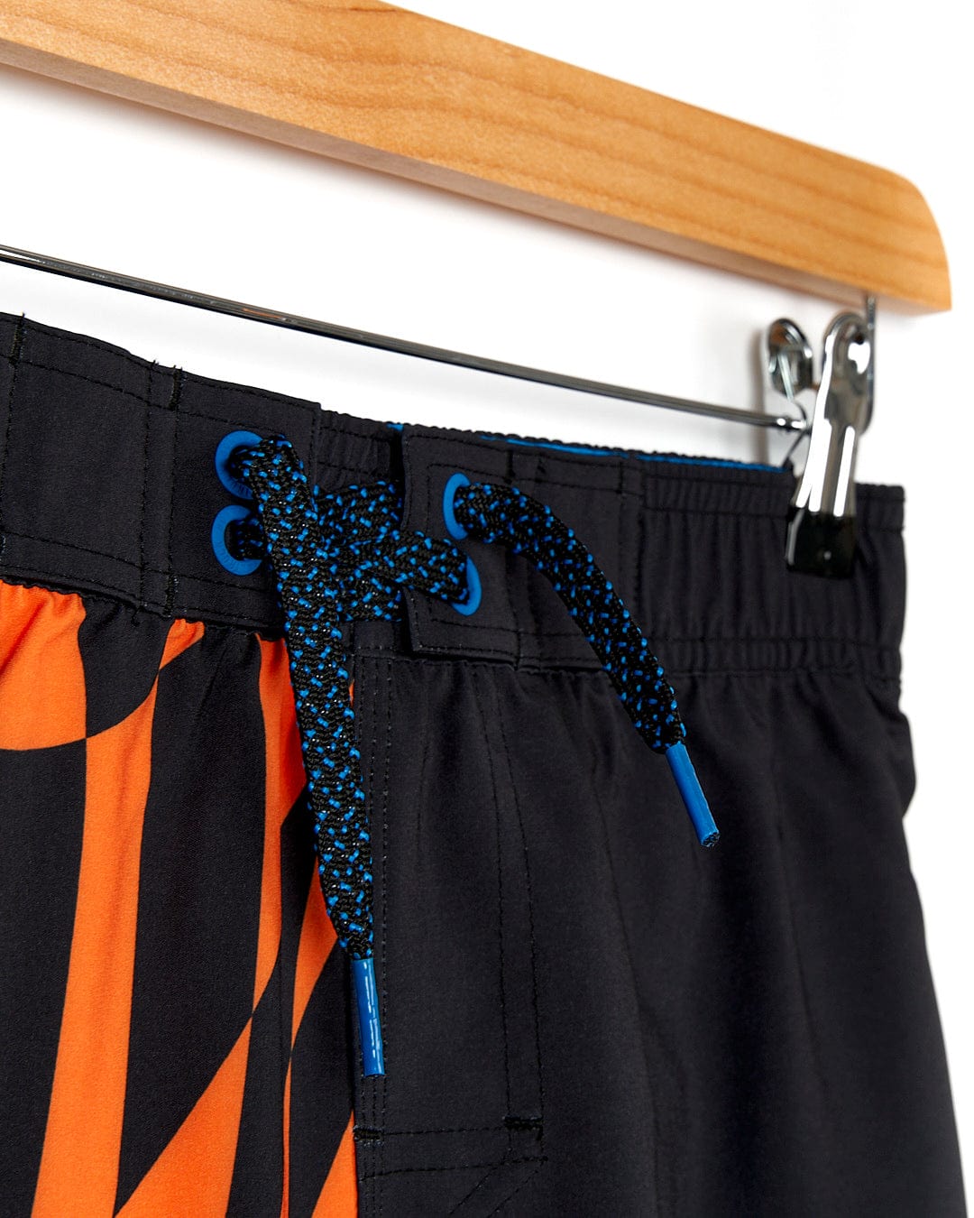 A Warped - Kids Boardshort - Black from Saltrock hanging on a hanger.
