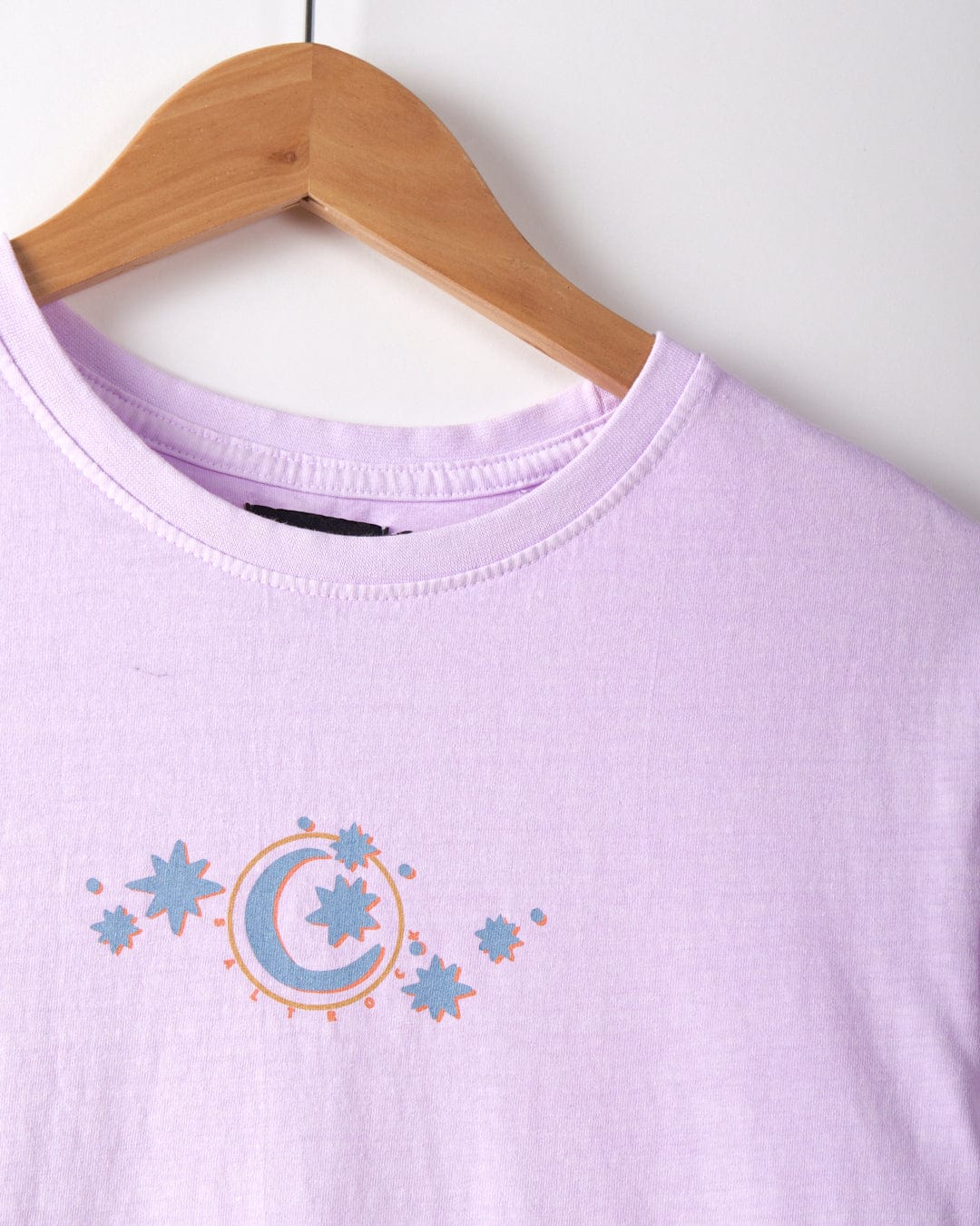 A pink crew fit t-shirt, crafted from 100% cotton, hangs gracefully on a wooden hanger. It features Saltrock graphics with a whimsical design.