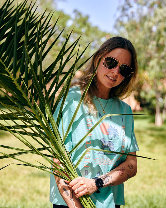 Woman in sunglasses and a Fierce Mind - Womens Cropped T-Shirt - Green, 100% cotton t-shirt holding a palm frond, standing in a sunny garden by Saltrock.