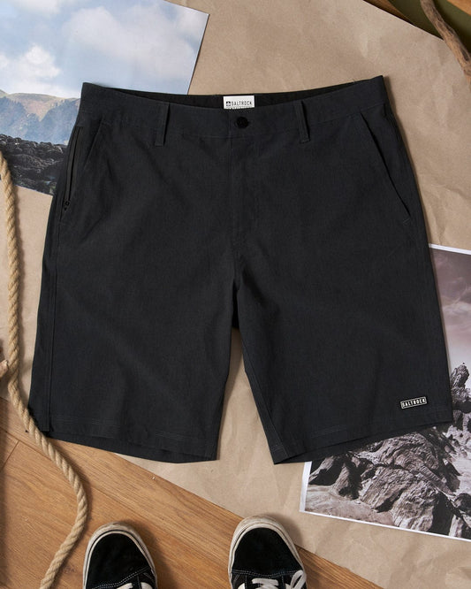 A pair of Saltrock Amphibian 2 - Mens Hybrid Boardshorts in black with belt loops next to a pair of sneakers.