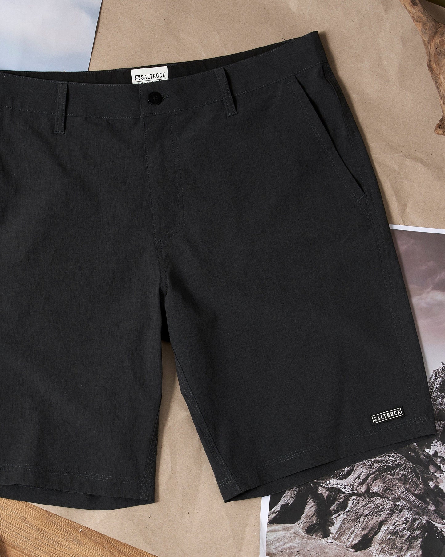 The Saltrock Amphibian 2 - Mens Hybrid Boardshorts - Black on a wooden table are machine washable.