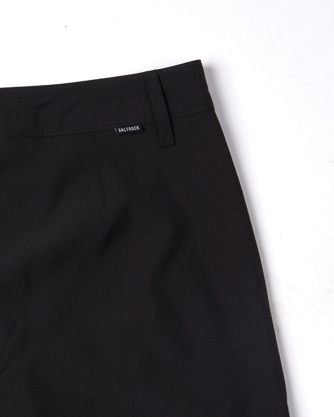 Close-up of a Saltrock black Amphibian boardshort on a white background, focusing on the waistband and zip fastening.