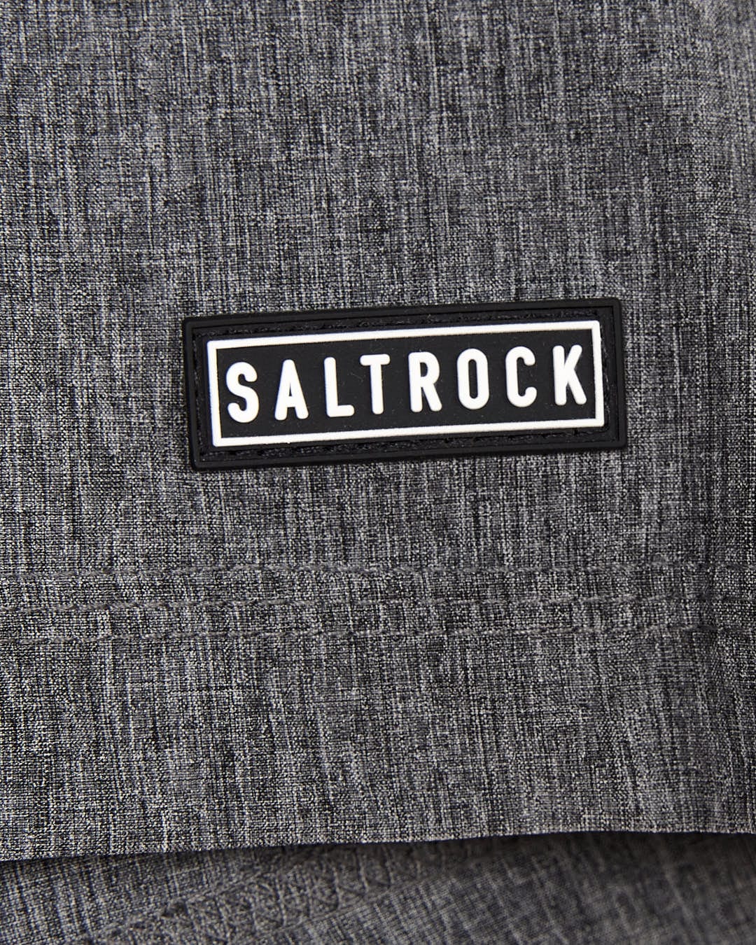 A close up of the Saltrock logo on a grey Amphibian - Kids Boardshorts shirt.