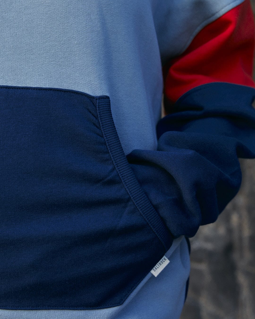 A man wearing a blue and red hoodie with Contrast paneling - the Anya Women's Pop Hoodie in Blue by Saltrock.