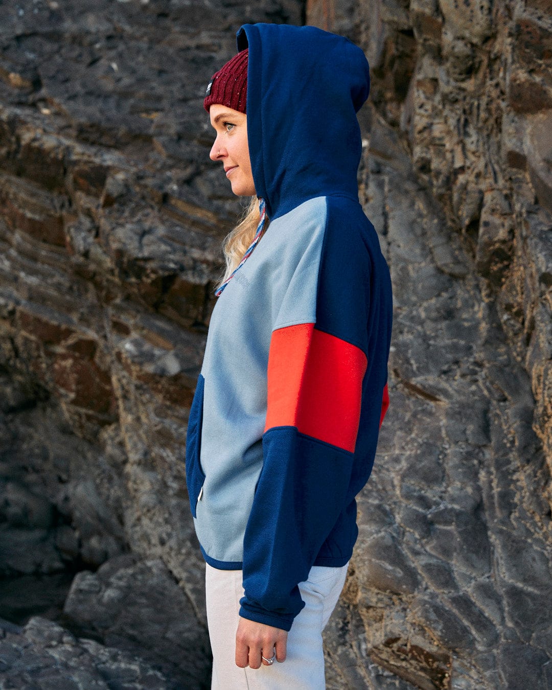 A woman wearing a Anya - Womens Pop Hoodie - Blue with contrast paneling in blue and red, featuring Saltrock branding.