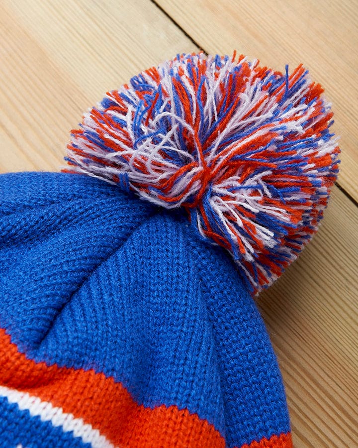 The Saltrock Apres - Beanie - Blue, featuring the iconic pom pom in blue, red, and white, is perfect for an apres ski look.