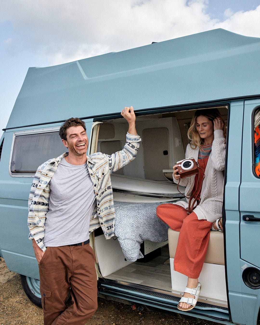 A man and woman standing in front of a blue VW camper van featuring an Aztec jacquard all over print, made from 100% Cotton.